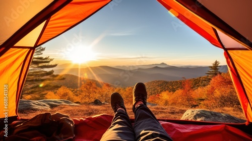A man enjoys the view of the autumn mountains while sitting in a tent. Hiking and digital detox concept. Contemplation of nature alone with your thoughts, away from the noise of cities.