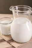 Glassware with tasty milk on table, closeup