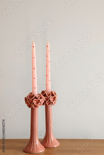 Beautiful pink wax candles on wooden table near white wall