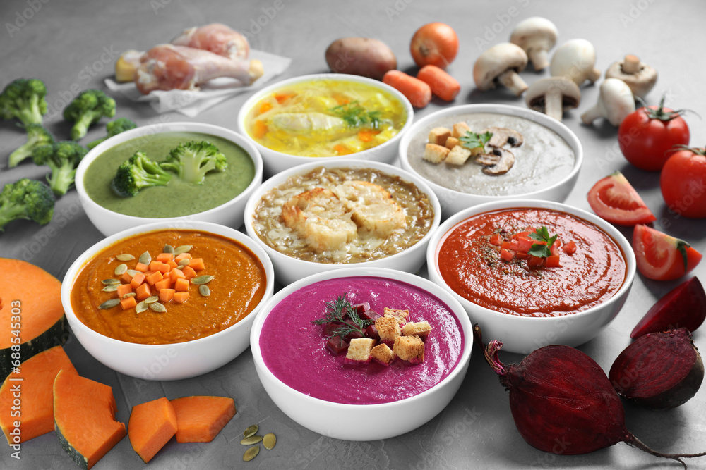 Tasty broth, different cream soups in bowls and ingredients on table, closeup Tasty broth, different cream soups in bowls and ingredients on table, closeup