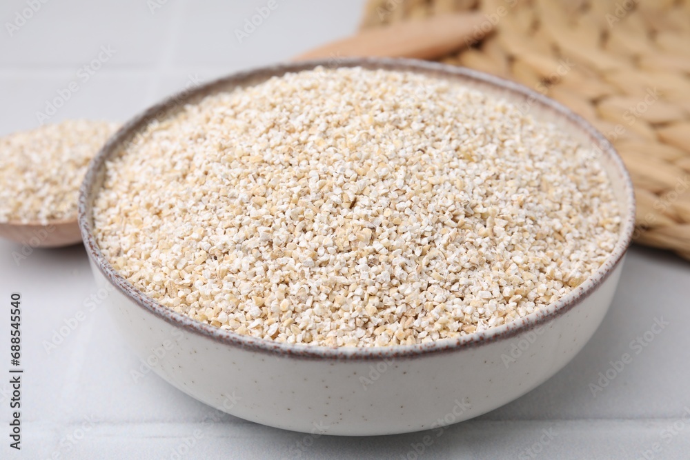 Raw barley groats in bowl on light table, closeup Raw barley groats in bowl on light table, closeup