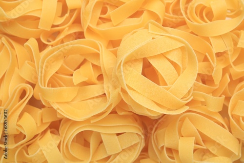 Raw tagliatelle pasta as background  top view