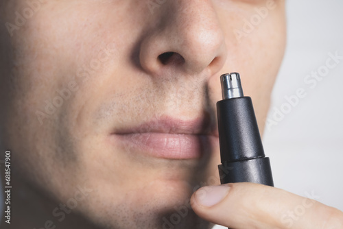Personal Care Concept. Man tending to his nasal hair with an electric trimmer. Close up view.