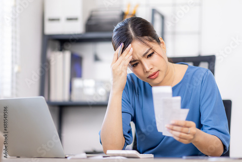 Frustrated desperate millennial woman checking bills for payments, holding receipts, getting upset about overspending, too high mortgage, insurance fees. Homeowner analyzing costs, expenses, budget photo