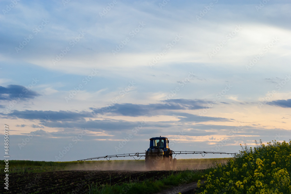 Tractor spraying pesticides on vegetable field with sprayer at spring Tractor spraying pesticides on vegetable field with sprayer at spring