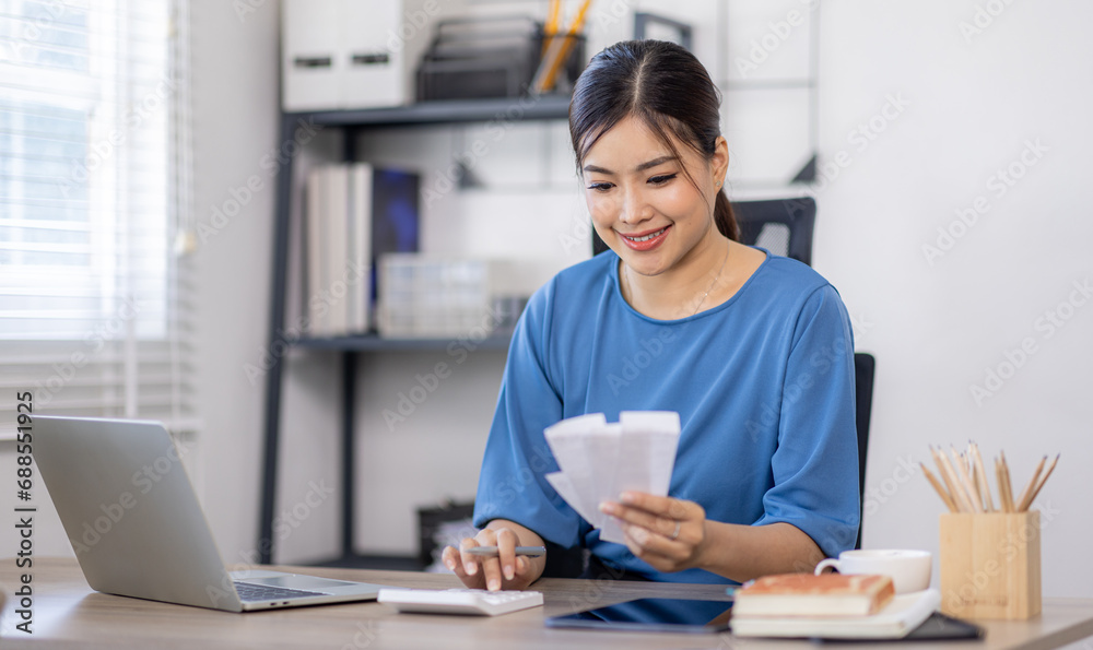 asian woman using calculator and calculate bills in home office. tax form us business income office Financial document. Tax time.Tax concept. asian woman using calculator and calculate bills in home office. tax form us business income office Financial document. Tax time.Tax concept.
