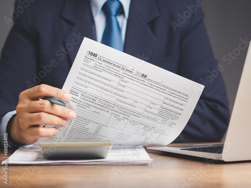 Businessman holding a form 1040. U.S. individual income tax return while sitting at the table