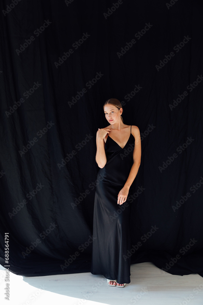 Portrait of a beautiful slender young woman in a black silk evening dress