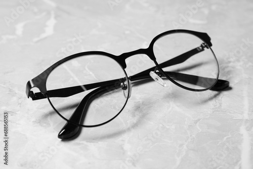 Glasses in stylish frame on grey marble table, closeup