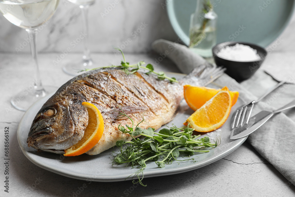 Seafood. Delicious baked fish served with orange and microgreens on light textured table, closeup Seafood. Delicious baked fish served with orange and microgreens on light textured table, closeup
