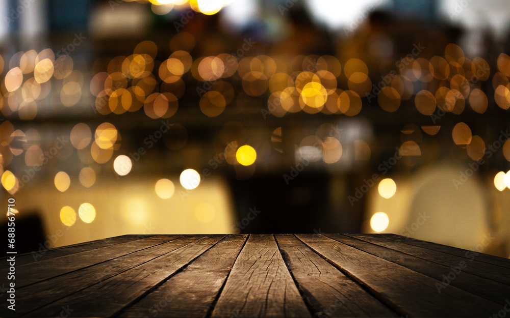 Empty wooden table top on blur light golden bokeh of cafe restaurant, bar in a dark background.