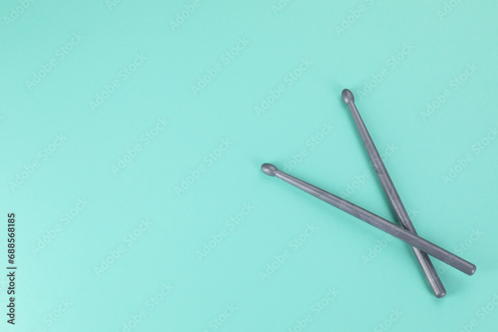 Two grey drumsticks on turquoise background, top view. Space for text Two grey drumsticks on turquoise background, top view. Space for text