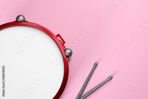 Children's drum with drumsticks on pink background, top view. Space for text photo