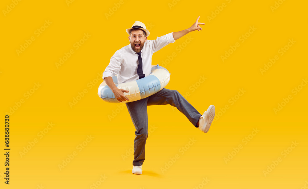 Full body photo of a happy funny man in sunglasses holding rubber ring and having fun isolated on studio yellow background. Funny tourist is going on summer holiday trip. Vacation and travel concept.