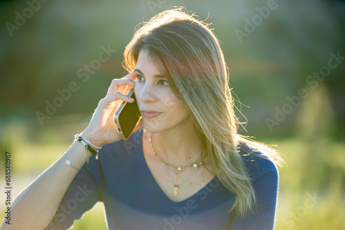 Close-up of a woman talking on the phone while relaxing outdoors.