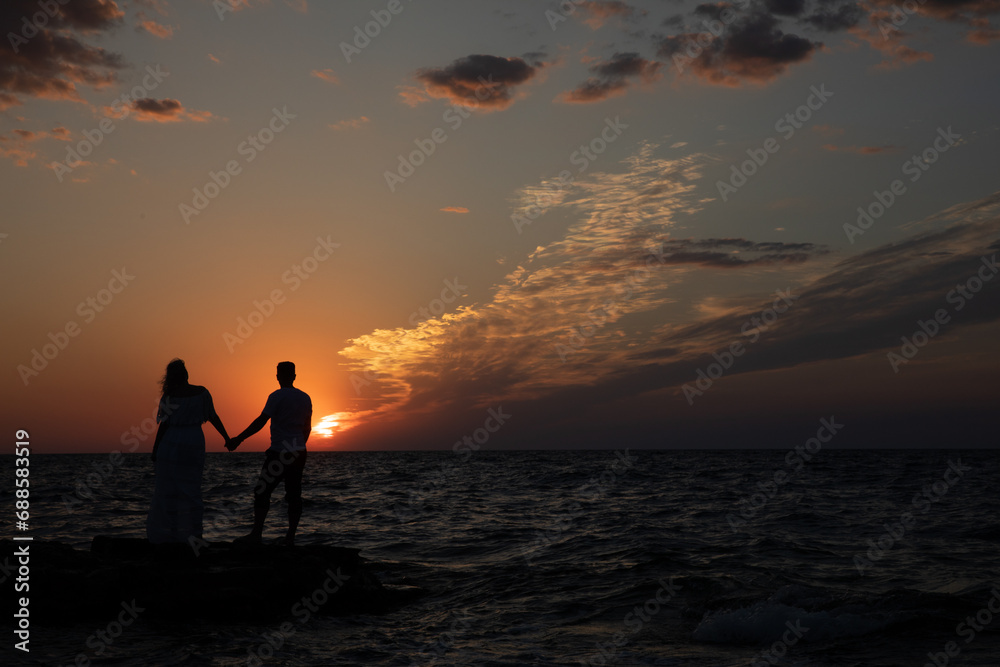 Silhouette of man and woman by the sea at sunset
