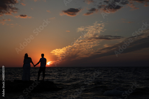 Silhouette of man and woman by the sea at sunset