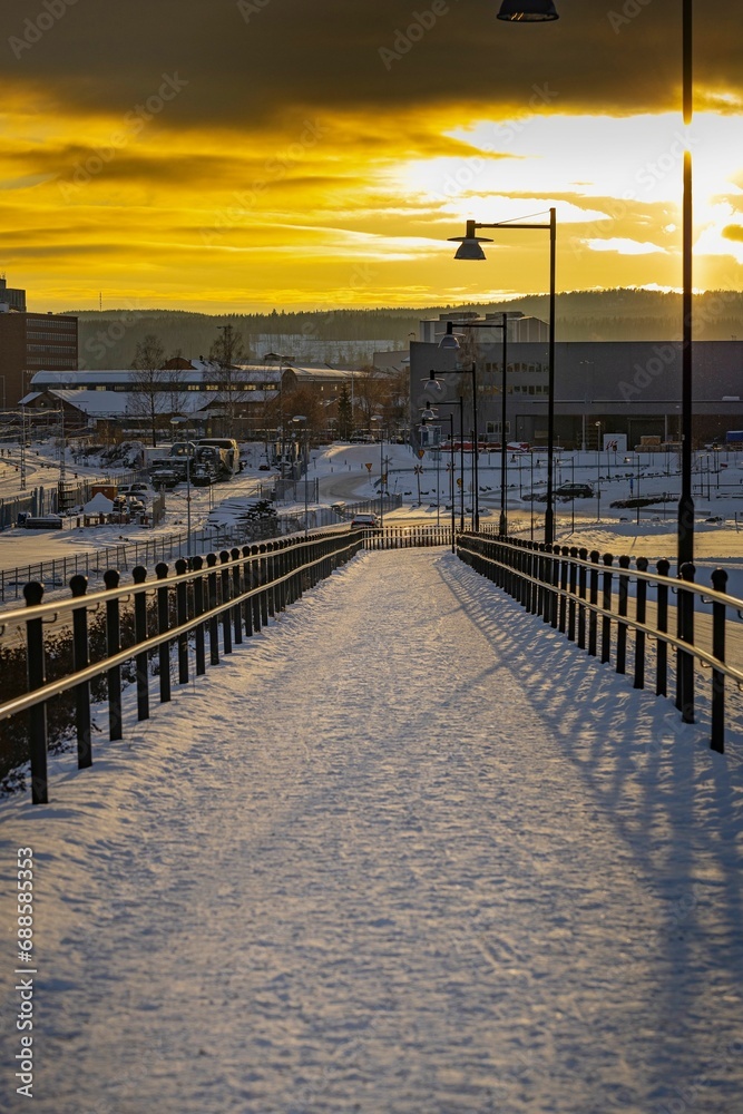 sun shines brightly on a snowy bridge over a city, Ludvika municipality Sweden