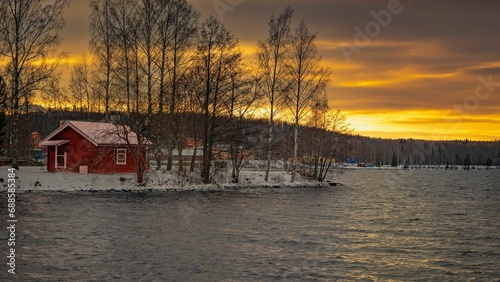 a lone red house sits on a small island on a lake in the winter, Ludvika municipality Sweden photo