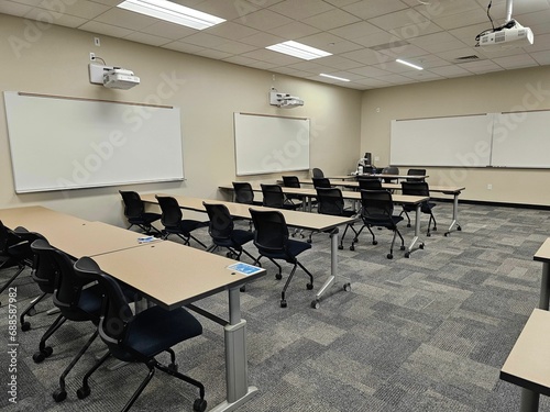 Empty classroom interior, with rows of desks and a projector suspended from the ceiling