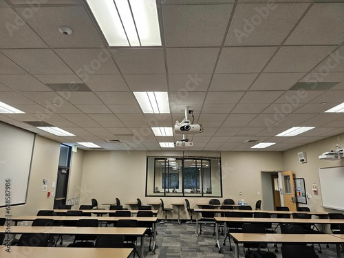 Empty classroom interior  with rows of desks and a projector suspended from the ceiling