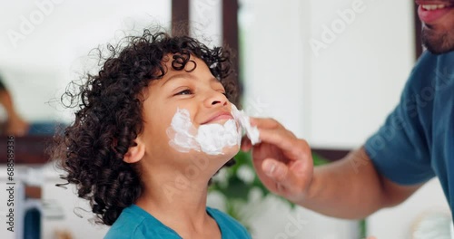 Father, child and playing with beard cream for grooming, beauty or fun bonding together in skincare at home. Happy dad applying lotion or after shave on son, kid or little boy for soft skin or facial photo