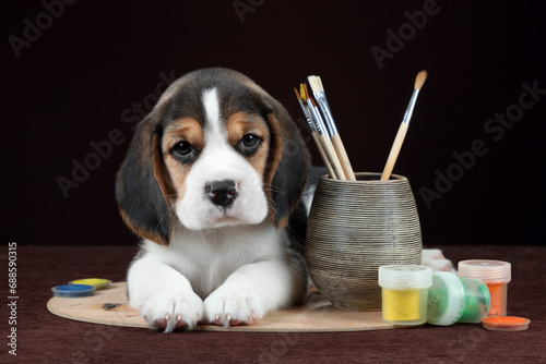 Cute little beagle puppy with brushes and paints