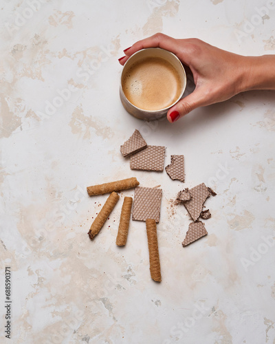 Dessert wafer and ceramic glass coffee on the decorative background style. Woman hand detail.