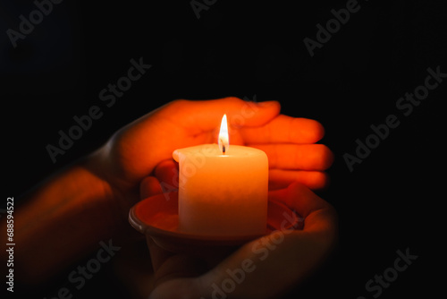 Religious concept.Boy holds in a hand a burning candle against black background.
