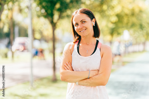 Portrait of athlete woman standing outdoors with crossed arms and looking at the camera.