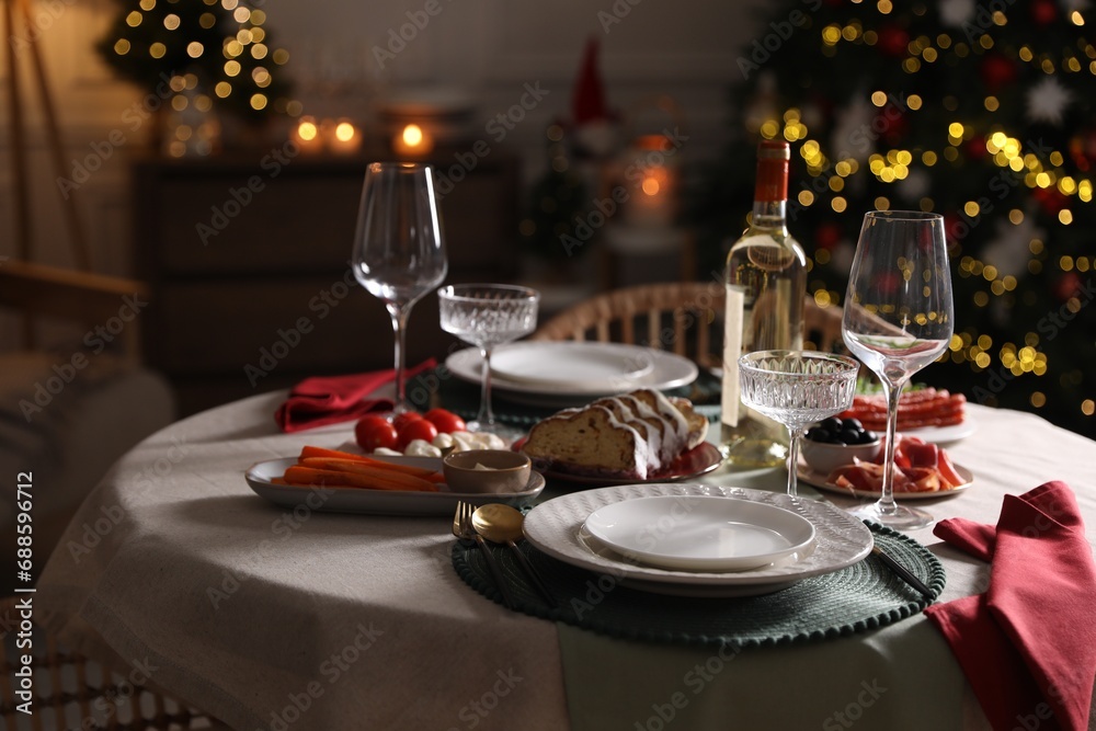 Christmas table setting with bottle of wine, appetizers and dishware indoors