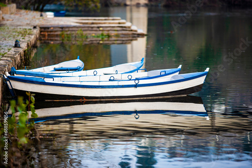 quatro barcos azuis e brancos na margem do rio. ambiente de outono inverno, margens em pedra antiga, reflexo dos barcos na água . photo