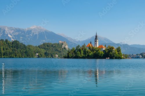 View of Lake Bled with St. Marys Church of Assumption on a small island on a sunny day. Lake with turquoise water. Slovenia, Europe. Mountains on background. © Lizaveta