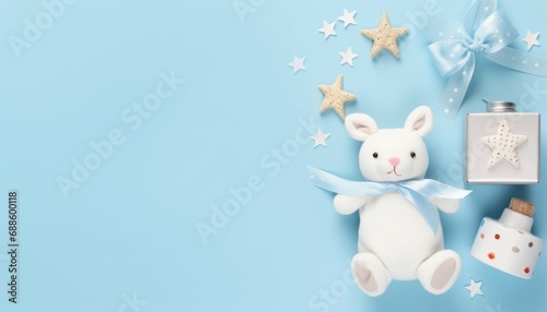 Baby accessories concept top view photo of gift box teether knitted bunny rattle toy and stars on isolated pastel blue background with empty space photo