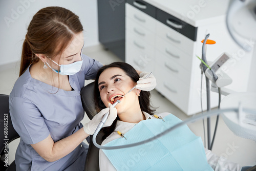 Beautiful young woman doing tooth examination in the dental office. Portrait of smiling girl on a dental chair in dentistry