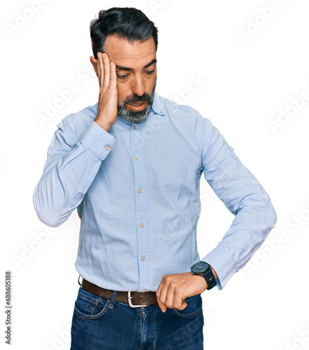 Middle aged man with beard wearing business shirt looking at the watch time worried, afraid of getting late © Krakenimages.com
