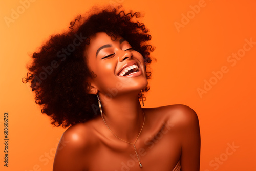  a black woman smiles in the studio on orange background. happy model