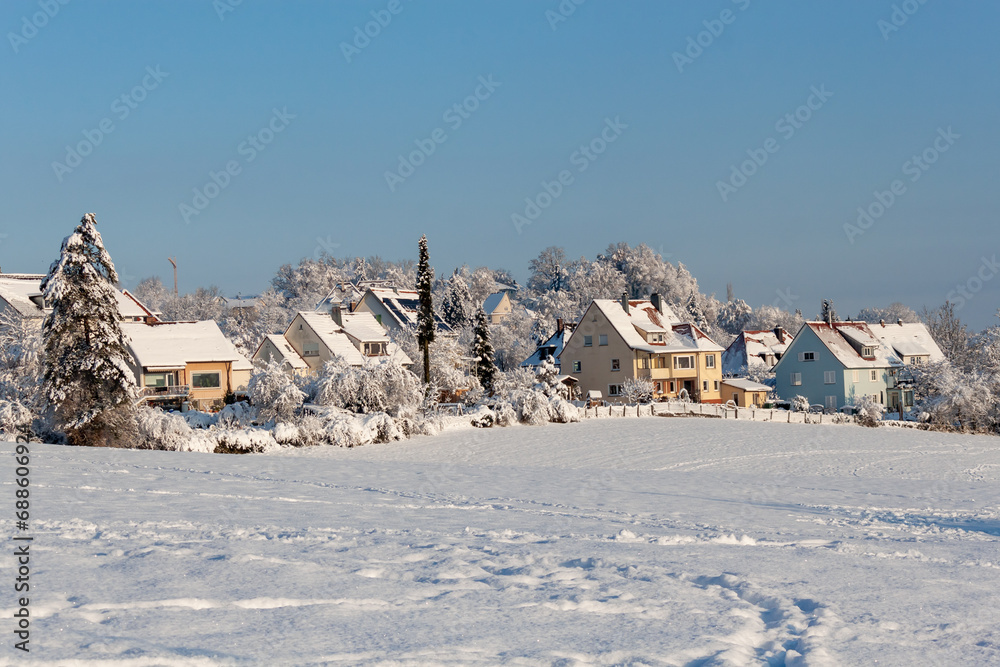 Beautiful winter in a European village - view of a snow-covered field against the backdrop of country houses