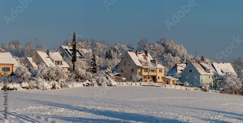 Beautiful winter in a European village - view of a snow-covered field against the backdrop of country houses