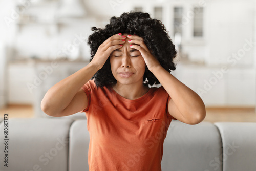Headache Concept. Young black woman suffering from migraine at home photo