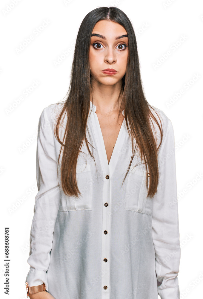 Young beautiful woman wearing casual white shirt puffing cheeks with funny face. mouth inflated with air, crazy expression. Young beautiful woman wearing casual white shirt puffing cheeks with funny face. mouth inflated with air, crazy expression.