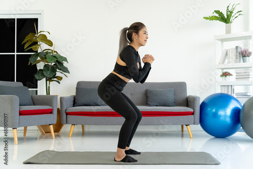 Asian woman Squatting on Yoga Mat in Living Room, © pixs4u