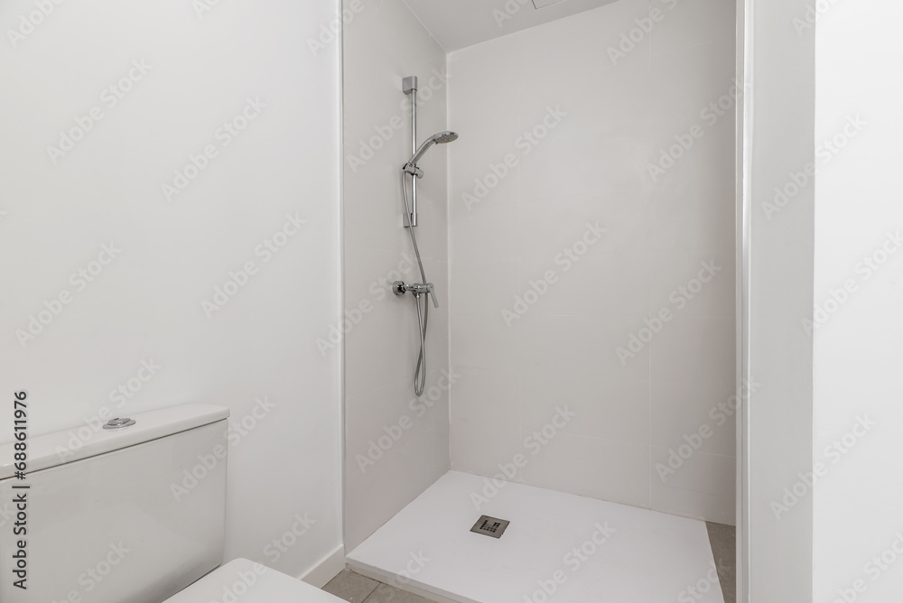 A bathroom with stoneware and white tiles, a shower cabin with a screen and a white resin floor with a drain A bathroom with stoneware and white tiles, a shower cabin with a screen and a white resin floor with a drain