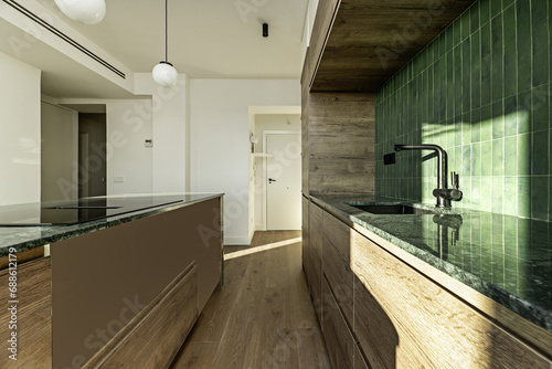 Kitchen with oak wood furniture, green granite countertops, island with the same countertop and tiles of the same tone on the backsplash