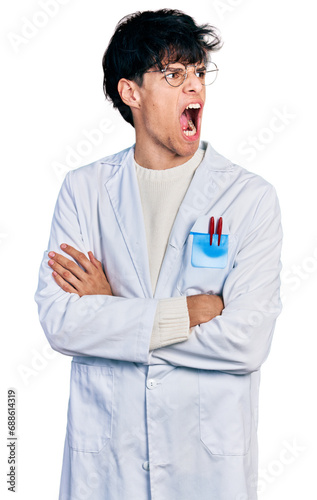 Handsome hipster young man with crossed arms wearing doctor uniform angry and mad screaming frustrated and furious, shouting with anger. rage and aggressive concept.