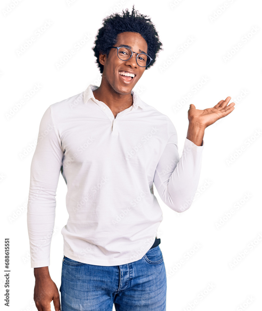 Handsome african american man with afro hair wearing casual clothes and glasses smiling cheerful presenting and pointing with palm of hand looking at the camera.