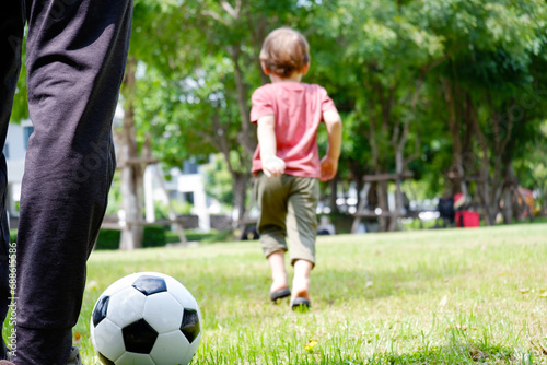 A boy runs and kicks football in the grass.