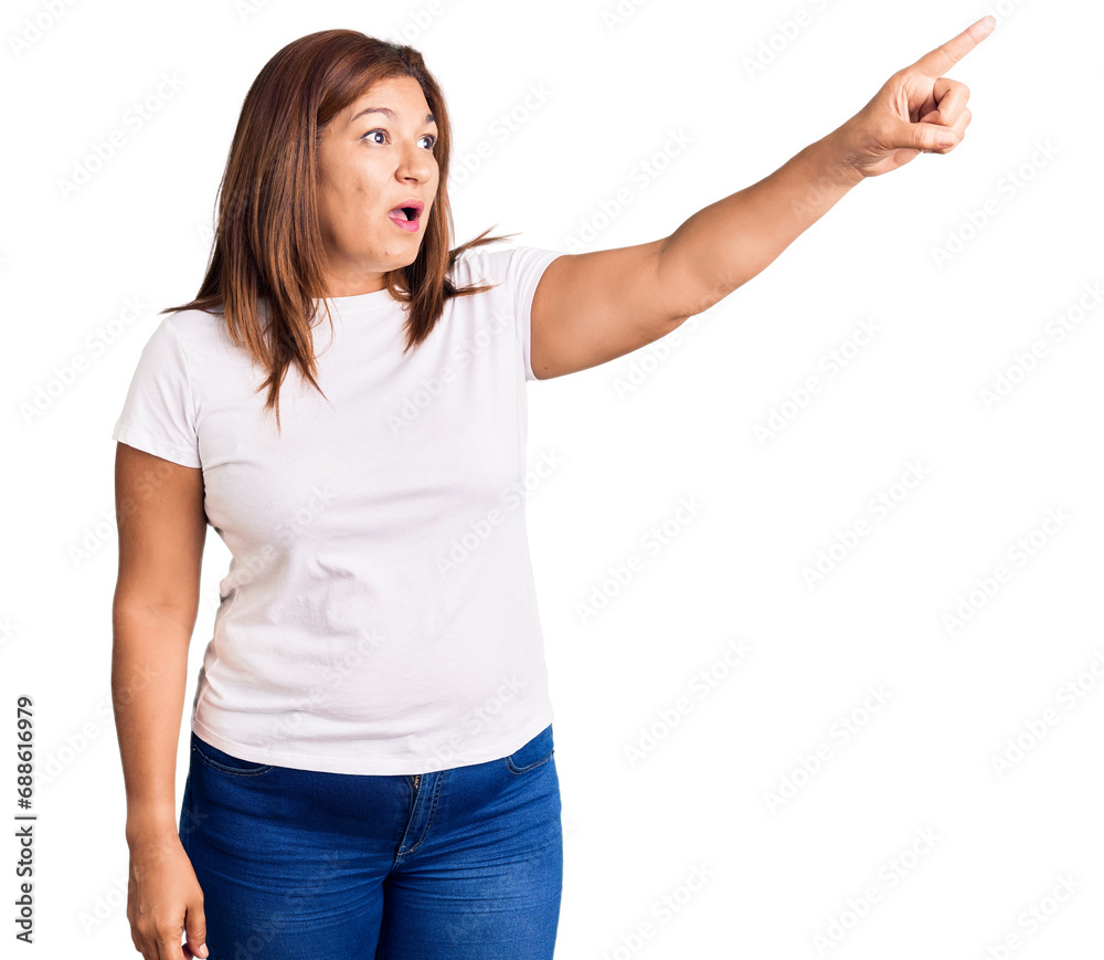 Middle age latin woman wearing casual white tshirt pointing with finger surprised ahead, open mouth amazed expression, something on the front