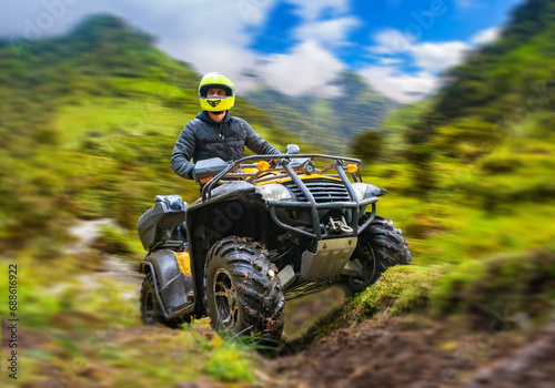 Man on ATV. Quadcyclist travels off-road. Extreme tourism. Guy nar blurred mountains. Quadcyclist under blue sky. Man with extreme hobby. ATV competition. Quad bike race. ATV hobby. photo