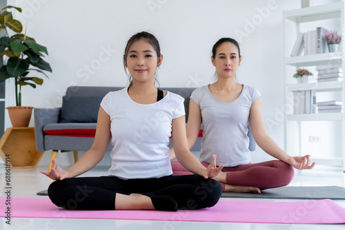 Two Women Meditating on Yoga Mat in Serene Setting